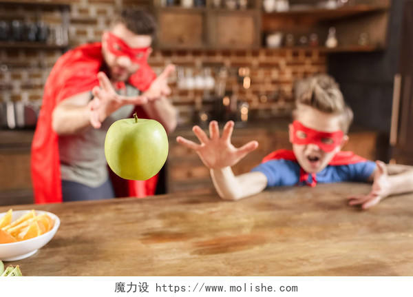父亲和儿子在玩苹果的红色超级英雄服装